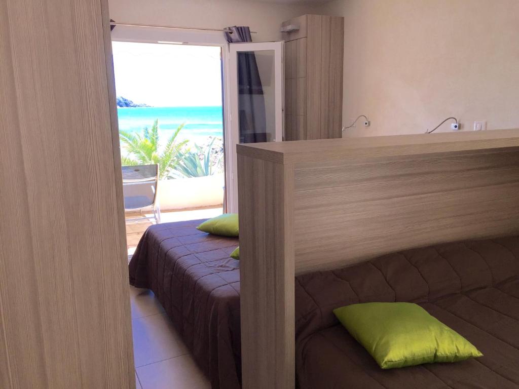 a bedroom with a bed and a view of the beach at Hôtel et Résidence Ta Kladia - Omigna in Cargèse