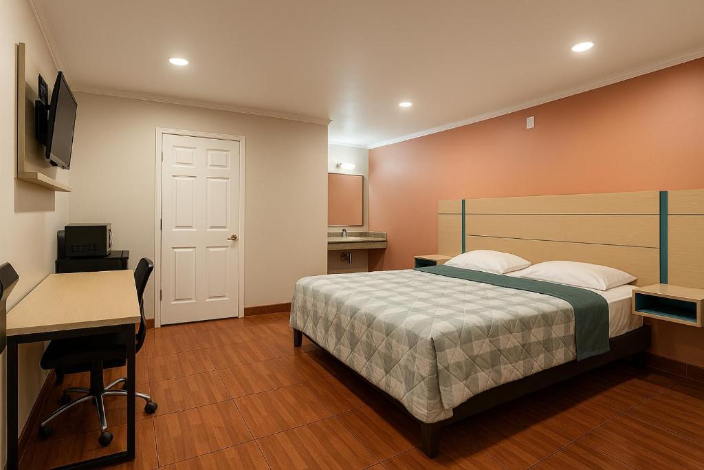 a bedroom with a bed and a desk and a computer at Sand Piper Motel - Los Angeles in Los Angeles