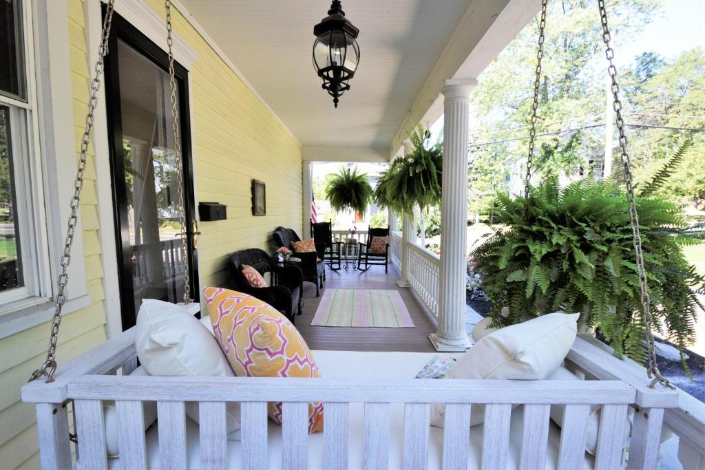 un porche con un sofá colgante en una casa en 34 State "Historic Luxury Suites" Skaneateles, en Skaneateles