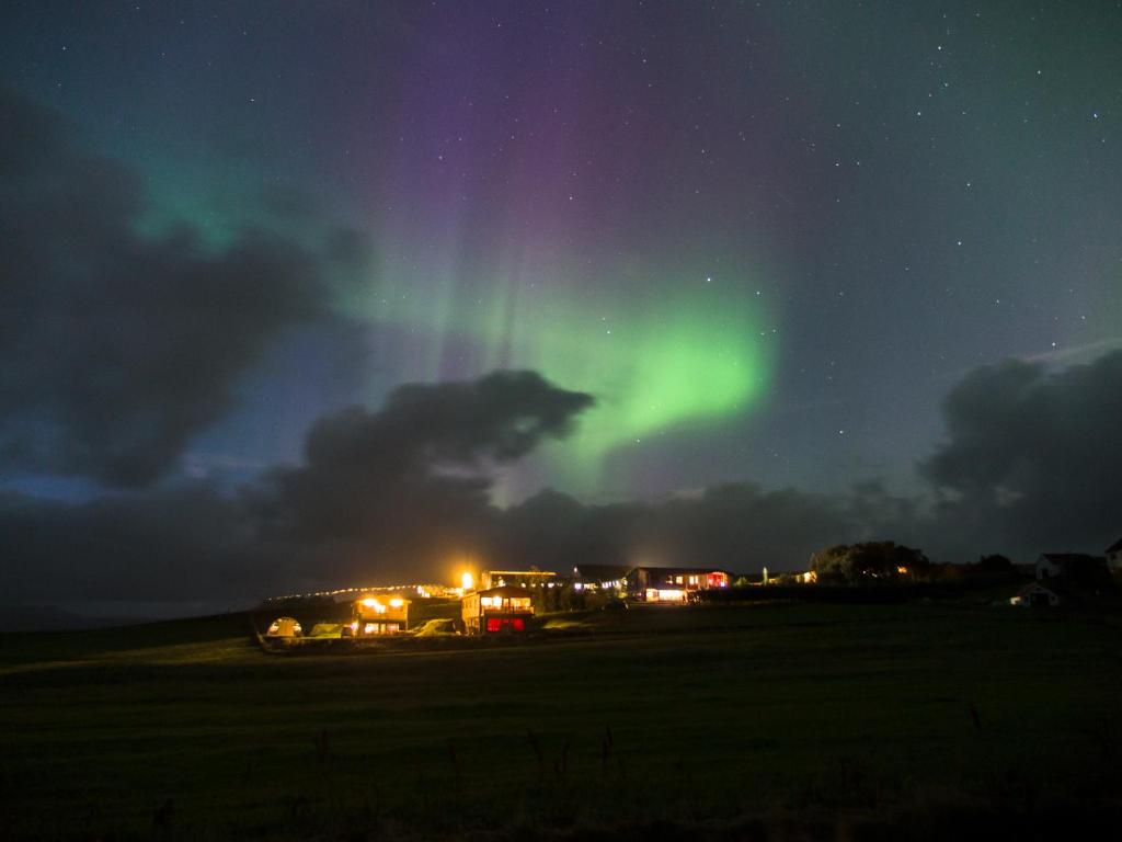 aurora na niebie nad polem w nocy w obiekcie Stóra-Mörk III Guesthouse w mieście Stora Mork