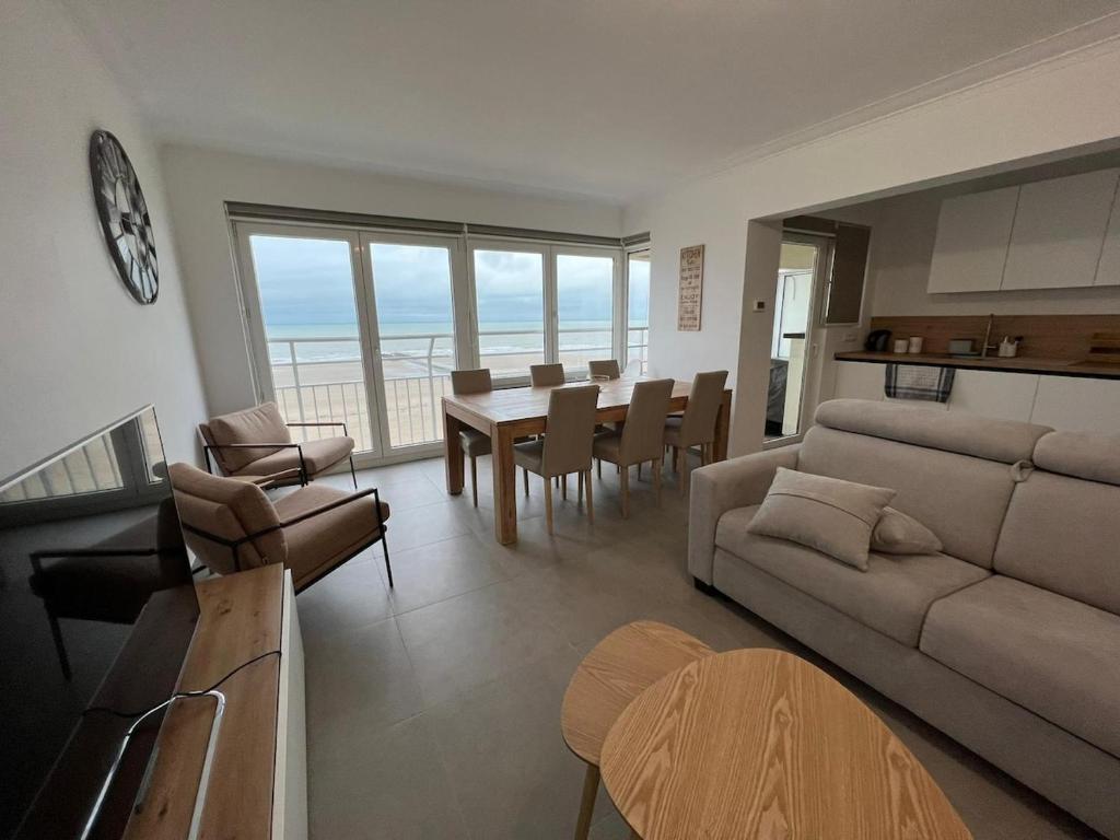 a living room with a couch and a table and chairs at En Bord de Mer in Middelkerke
