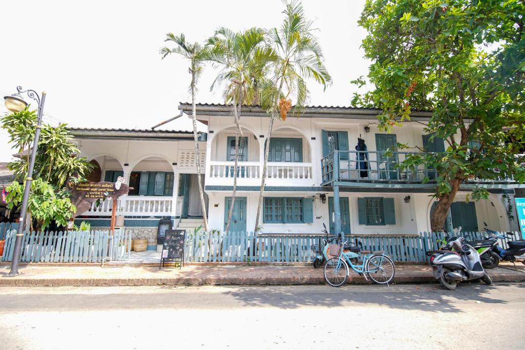 ein weißes Haus mit davor geparkten Motorrädern in der Unterkunft Chair Riverside in Luang Prabang