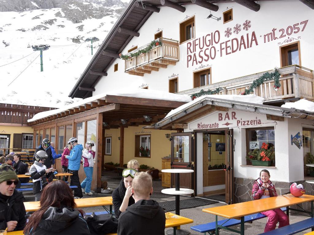 a group of people sitting at tables in front of a building at Rifugio Fedaia in Malga Ciapela