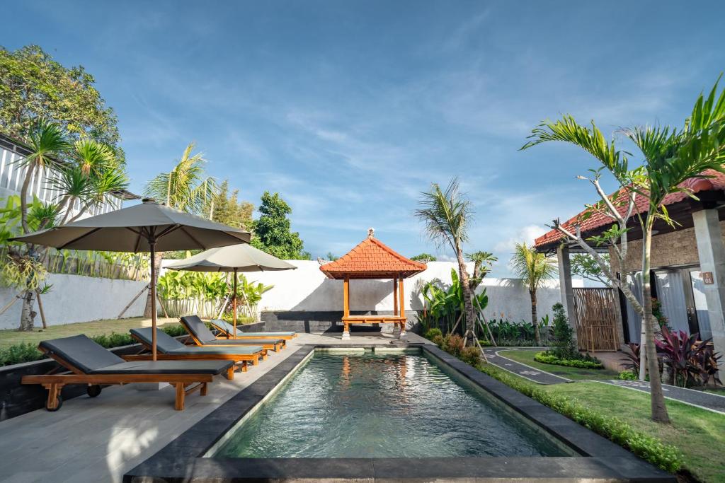 Una piscina con sillas y sombrillas al lado de una casa. en Ulu Apsura Villas, en Uluwatu