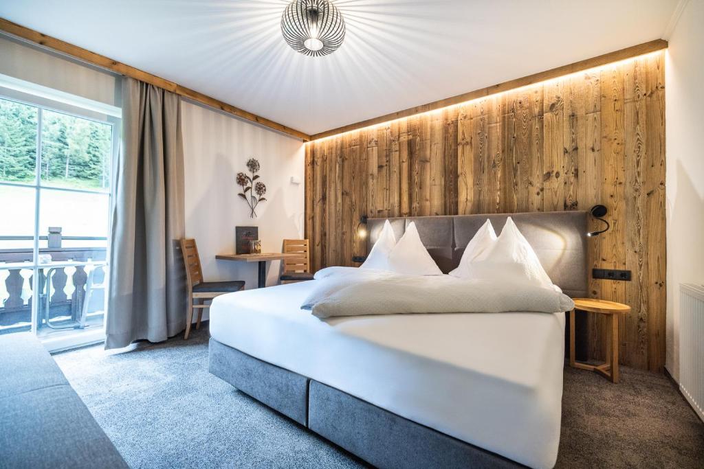 una camera con un letto bianco e una parete in legno di Wechslerhof a Flachau