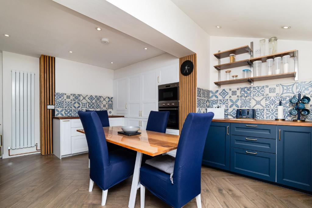 ピーブルスにある3 Bed House-Free Parkingのキッチン(木製テーブル、青い椅子付)