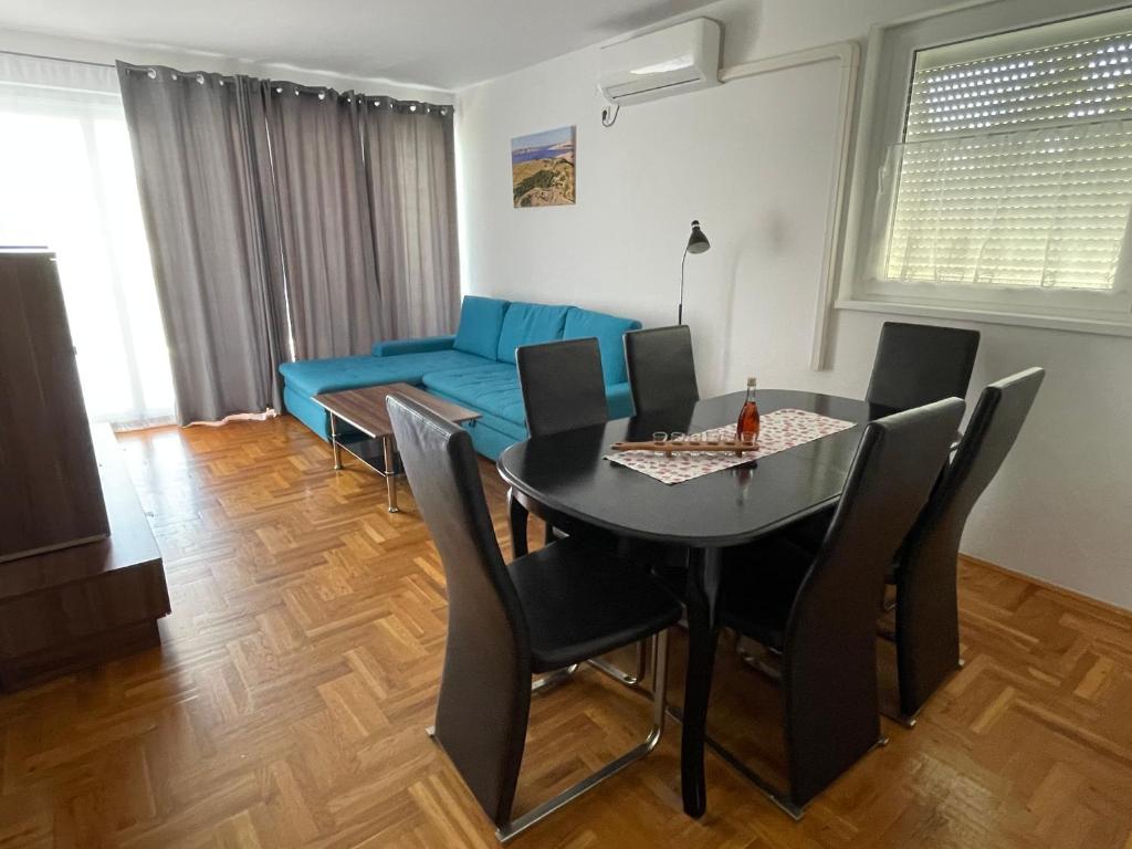 a living room with a table and a blue couch at Kristina Apartmanház in Dobrinj