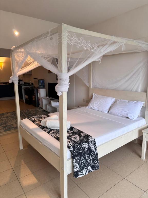 a white bed with a canopy in a room at Goldensun Resort Studio in Diani Beach