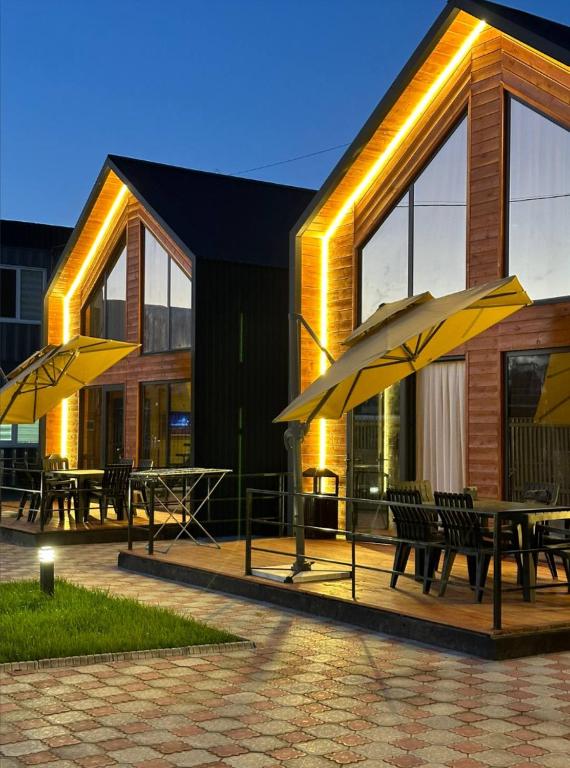 two tables and umbrellas in front of a building at Lake Villas Issyk-Kul in Cholpon-Ata