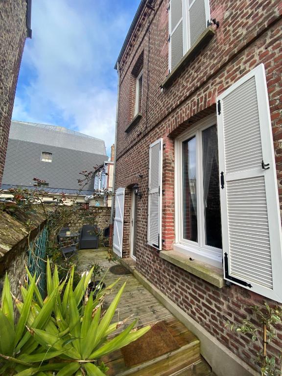 a brick house with white shutters and a patio at Chambre D'hôte Villa Maurice in Étretat