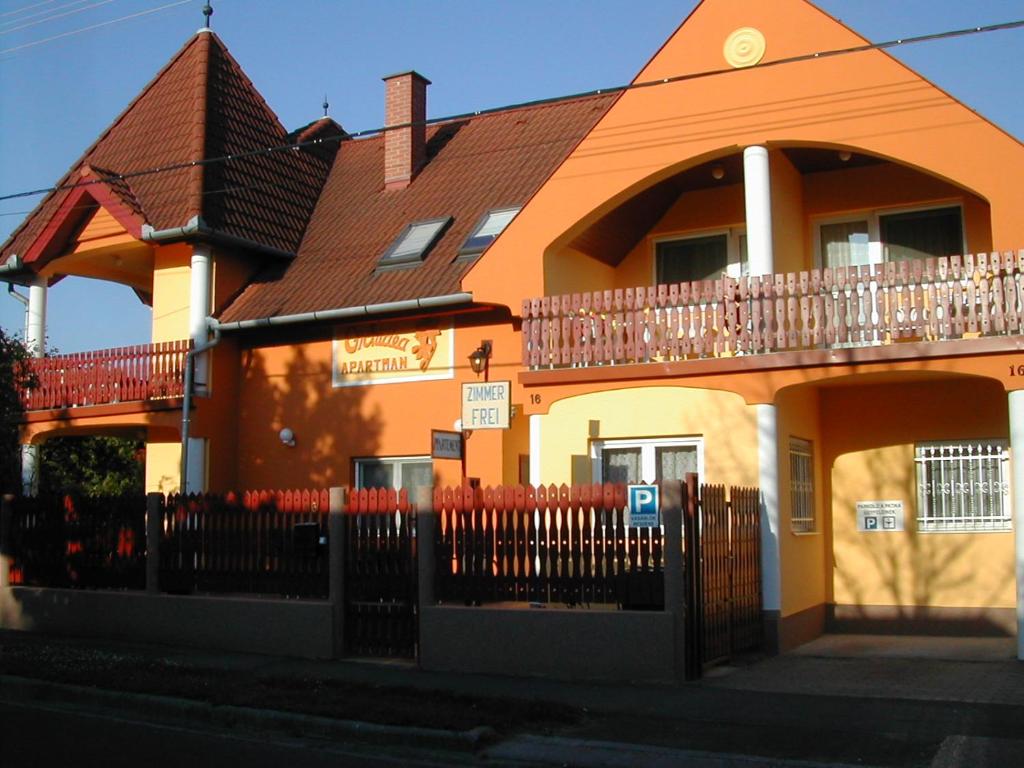 ヘーヴィーズにあるOrchidea Apartmanの塀の前のオレンジ色の家