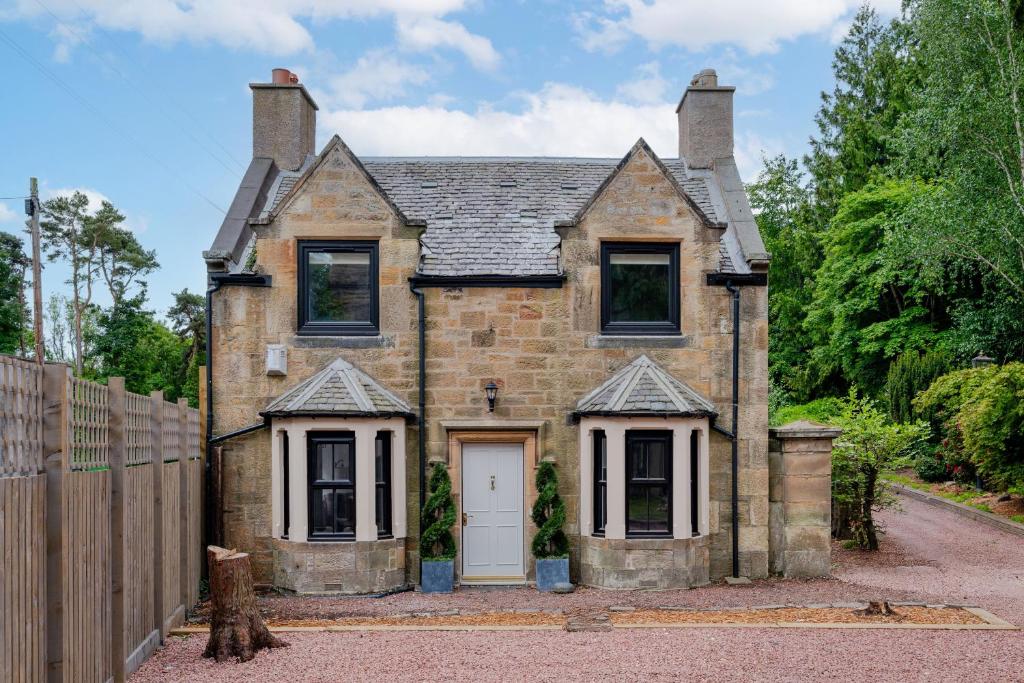 2 Bedroom Cottage-Free Parking في Newtongrange: منزل من الطوب القديم مع باب أبيض