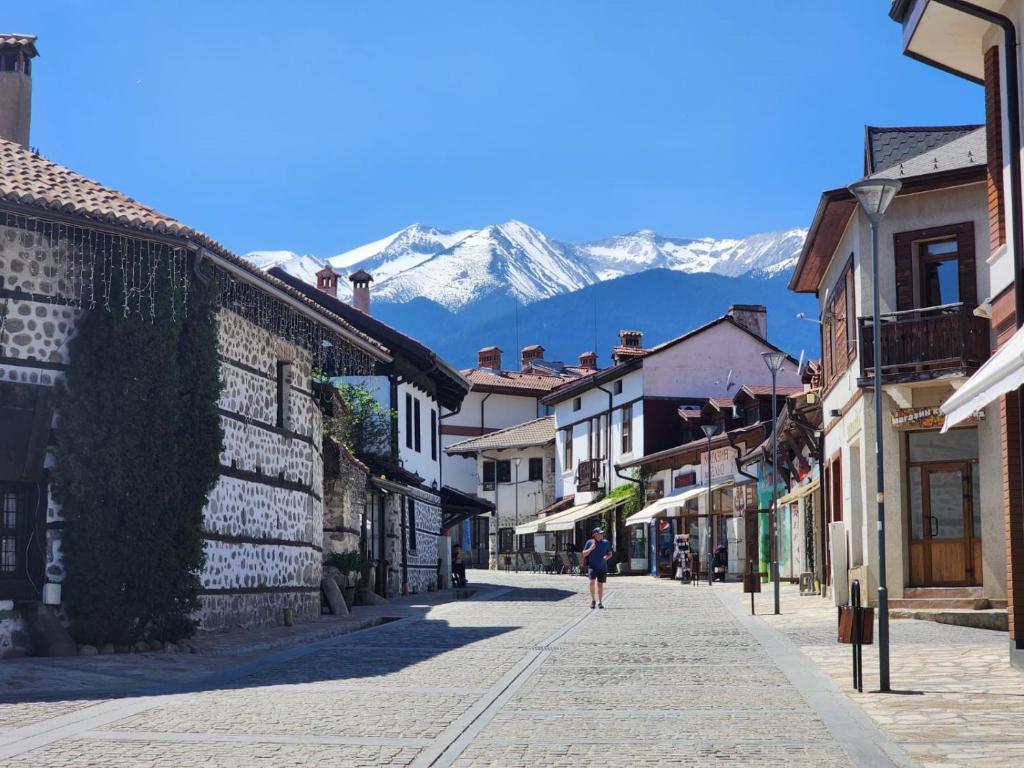 eine Person, die eine Straße mit Bergen im Hintergrund entlang geht in der Unterkunft Trinity Apartment & Pool with Spa Near Center in Bansko