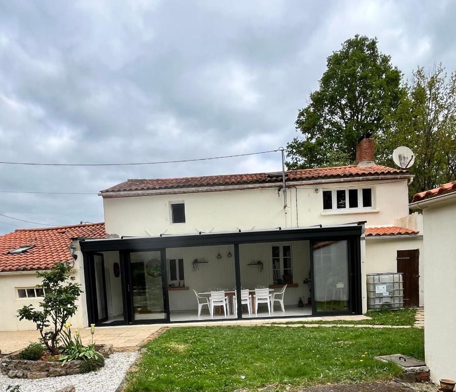 une maison blanche avec des portes en verre et une cour dans l'établissement Misenga, à Beaulieu-sous-la-Roche