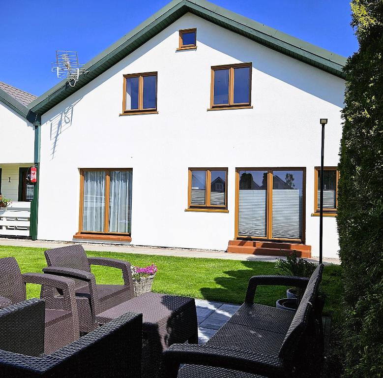 a white house with chairs in front of it at Dom Wakacyjny Zielone Wzgórze in Mielno