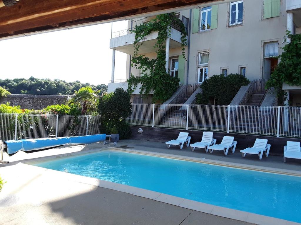 une piscine avec des chaises à côté d'un bâtiment dans l'établissement Bilboquet, à Vals-les-Bains