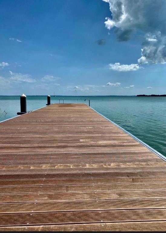 a wooden pier on the water with a blue sky at Fűzliget2 - Balaton Bliss in Balatonfůzfő