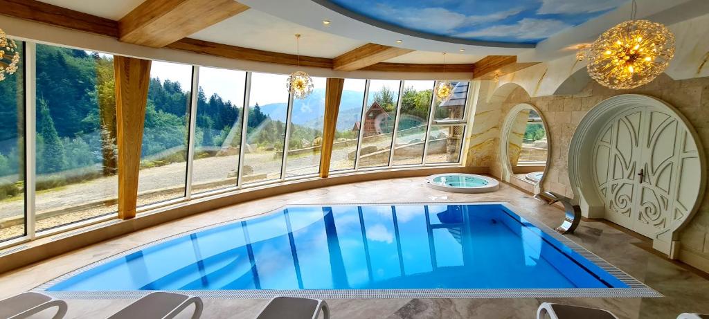 a large swimming pool in a room with windows at Krupówka Mountain Resort Wellness & SPA Szczyrk in Szczyrk