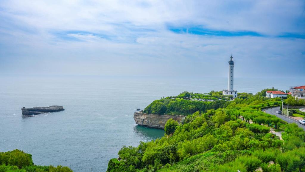 un phare sur une colline à côté d'une masse d'eau dans l'établissement Studio Résidence Régina et golf vue mer, à Biarritz