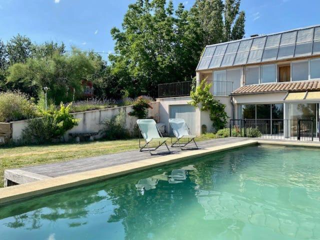 une piscine avec deux chaises à côté d'une maison dans l'établissement Le Pré de la Reyne, à Sault