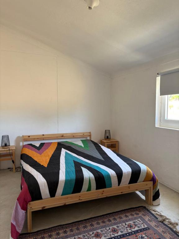 una camera da letto con un letto con una coperta colorata di QUINTA DA CORTE a Santiago do Cacém