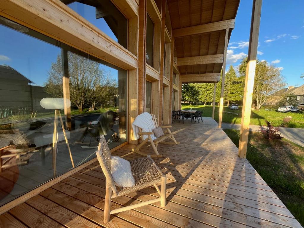 a porch of a house with rocking chairs and windows at Coeur Cévennes Wooden Cottage in Camprieu
