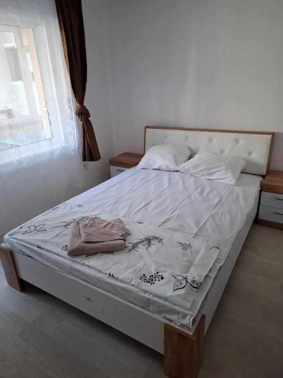 a bedroom with a bed with white sheets and a window at Guest House Damyanov in Ravda