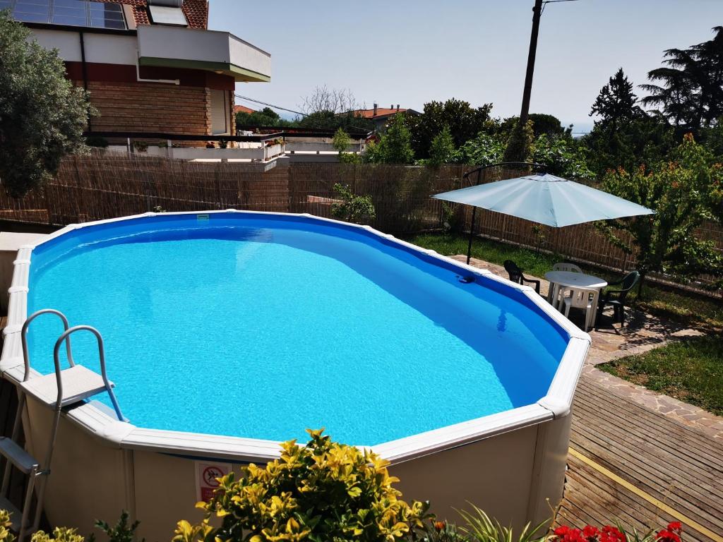 a large blue swimming pool with a table and an umbrella at Casa Cavallaro con Piscina estiva, giardino e parcheggio in Pescara