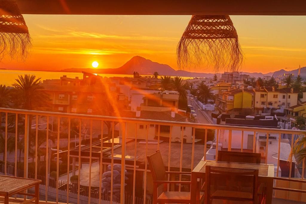 a balcony with a view of a city at sunset at AP-7 XimoApartments con VISTAS ESPECTACULARES AL MAR in Oliva
