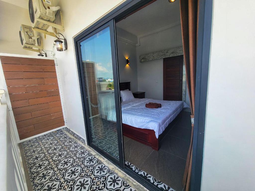 Una habitación con una cama y una puerta corrediza de vidrio. en Ranisa Kampot, en Kampot