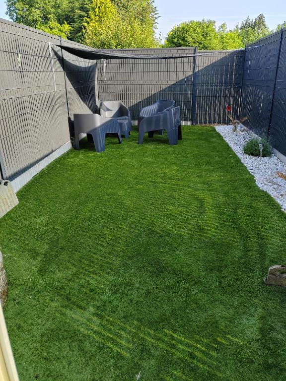 une petite cour arrière avec deux bancs et de l'herbe dans l'établissement Le Gîte de Ambre, à Grand