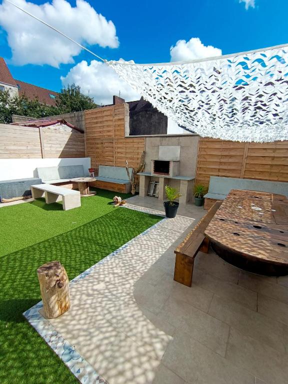 d'une terrasse avec une table, un banc et une pelouse. dans l'établissement Escapade à la plage, à Le Portel