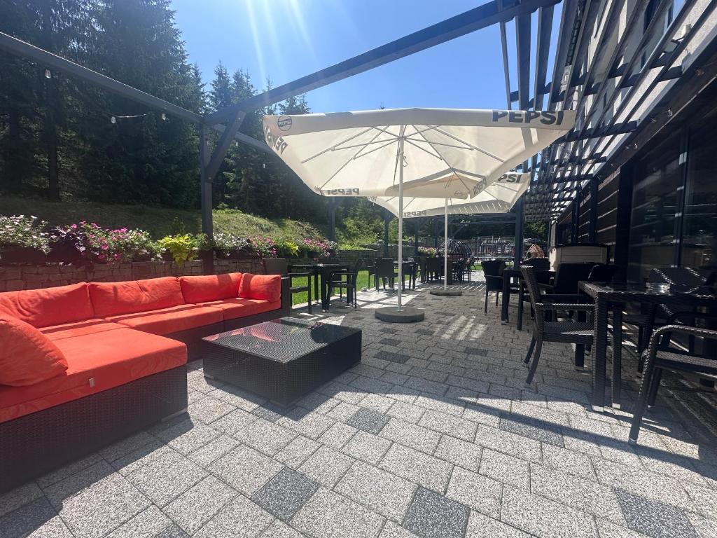 patio z kanapą, stołami i parasolem w obiekcie Hotel Jakuszyce Sport & Spa w Szklarskiej Porębie