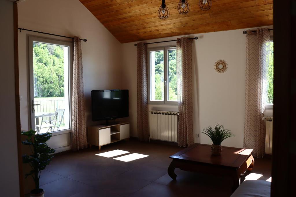 - un salon avec une télévision et 2 fenêtres dans l'établissement Maison garde de barriere, à Canilhac