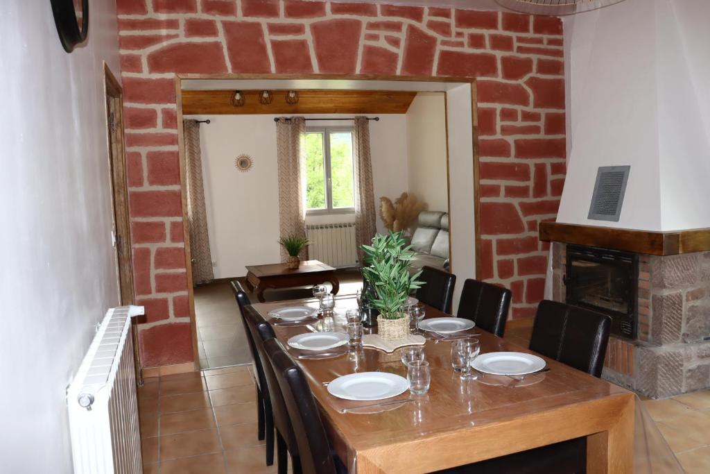 a dining room with a table and a brick wall at Maison Garde Barriere in Canilhac