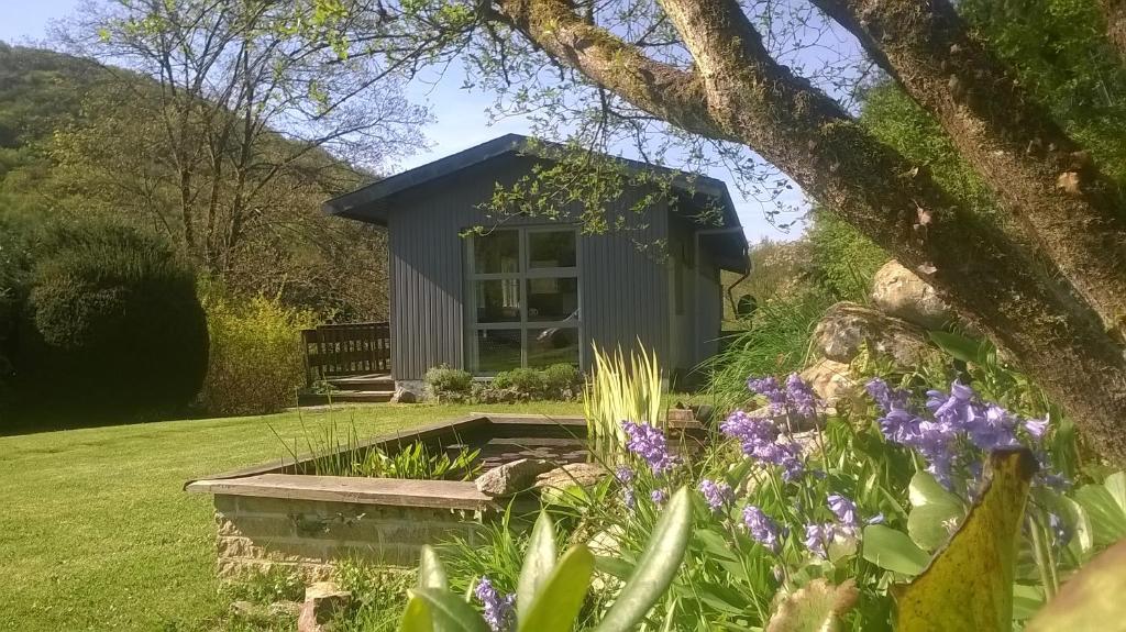 ein kleiner Schuppen in einem Garten mit lila Blumen in der Unterkunft Au Phil des Saisons in Arbre