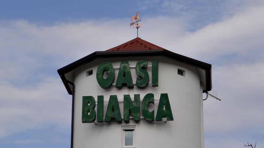 uma torre de relógio com um sinal em cima em Oasi Bianca em Pomposa