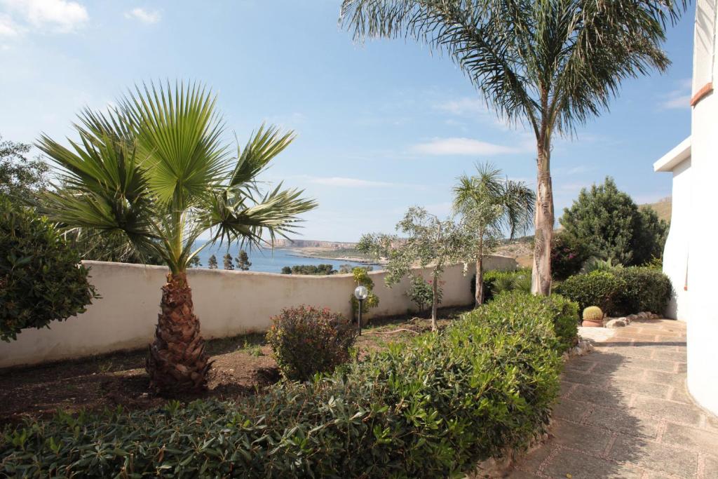 a walkway with palm trees and the ocean in the background at Country Villa San Vito Bay in San Vito lo Capo