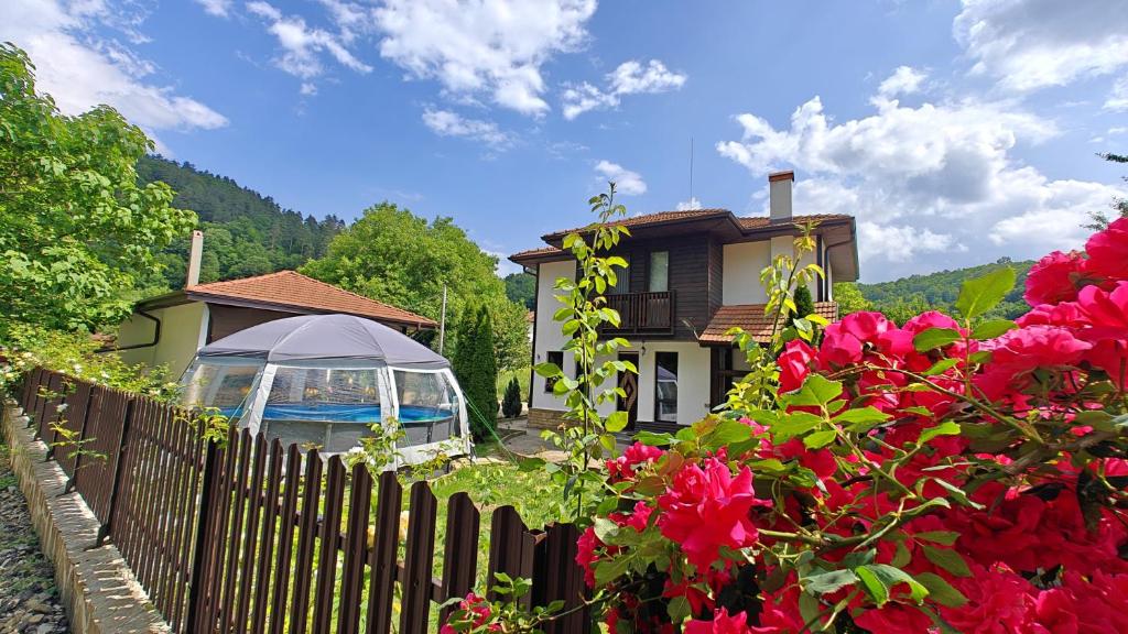 a house with a fence and red flowers at Къщи за гости Тепавица - Pool & Coworking in Tryavna