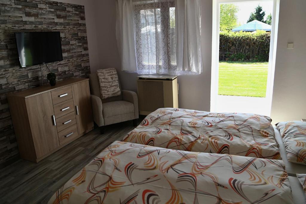 a bedroom with two beds and a tv and a chair at Apartmány Adriana in Veľký Meder