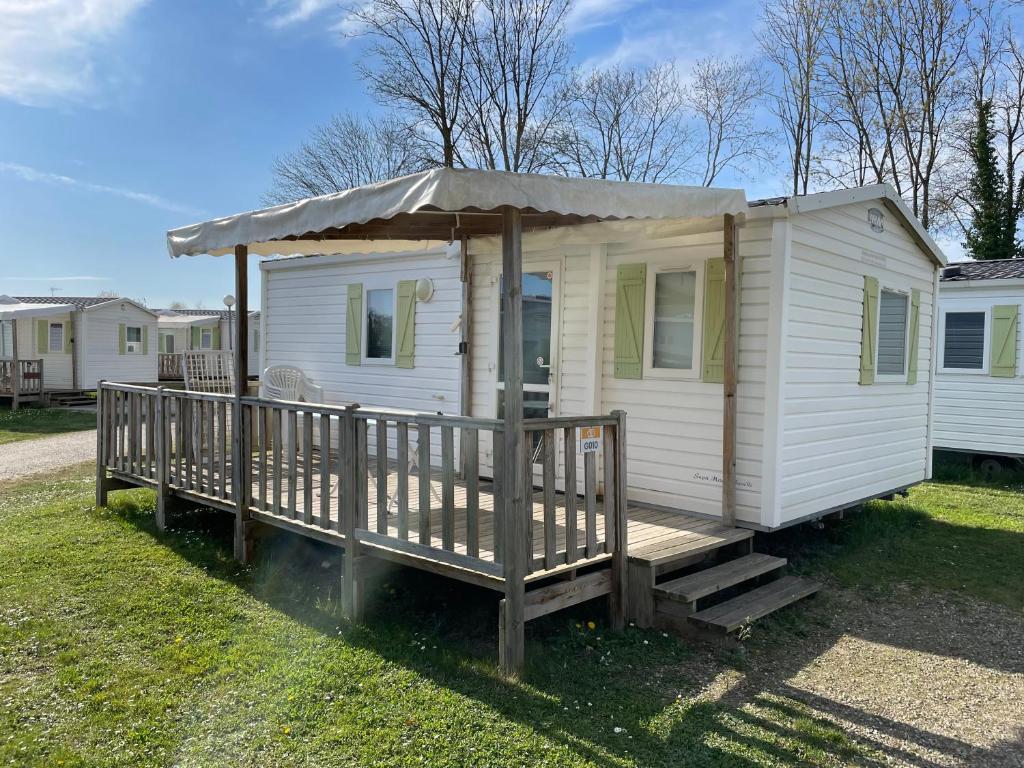 une petite maison blanche avec une terrasse couverte sur l'herbe dans l'établissement Mobil-Home proche Europa-Park, à Boofzheim
