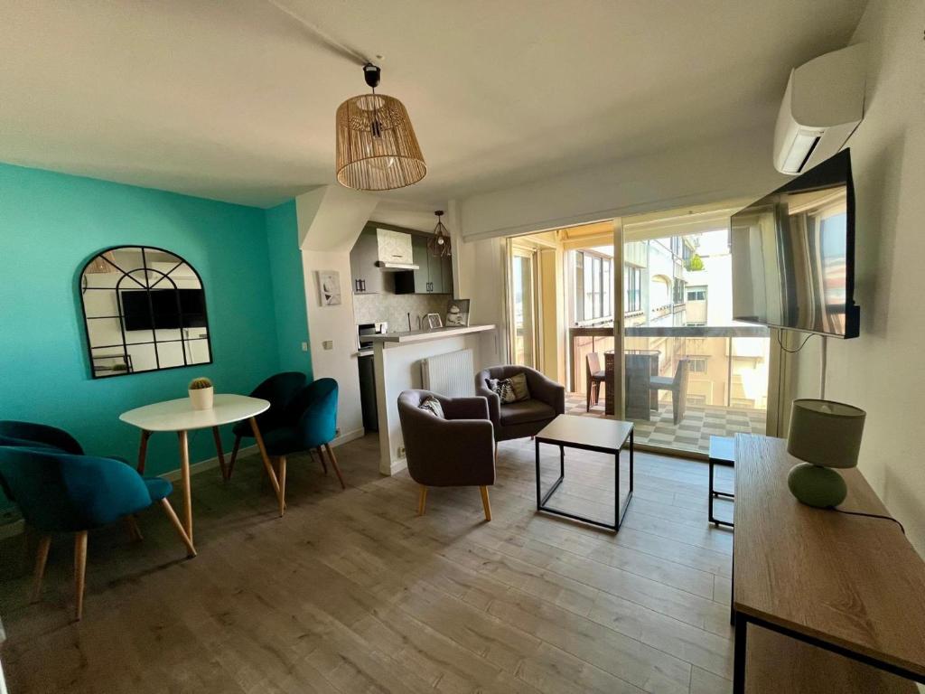 - un salon avec des murs bleus, une table et des chaises dans l'établissement Center Bay Studio Sky 7, à Antibes