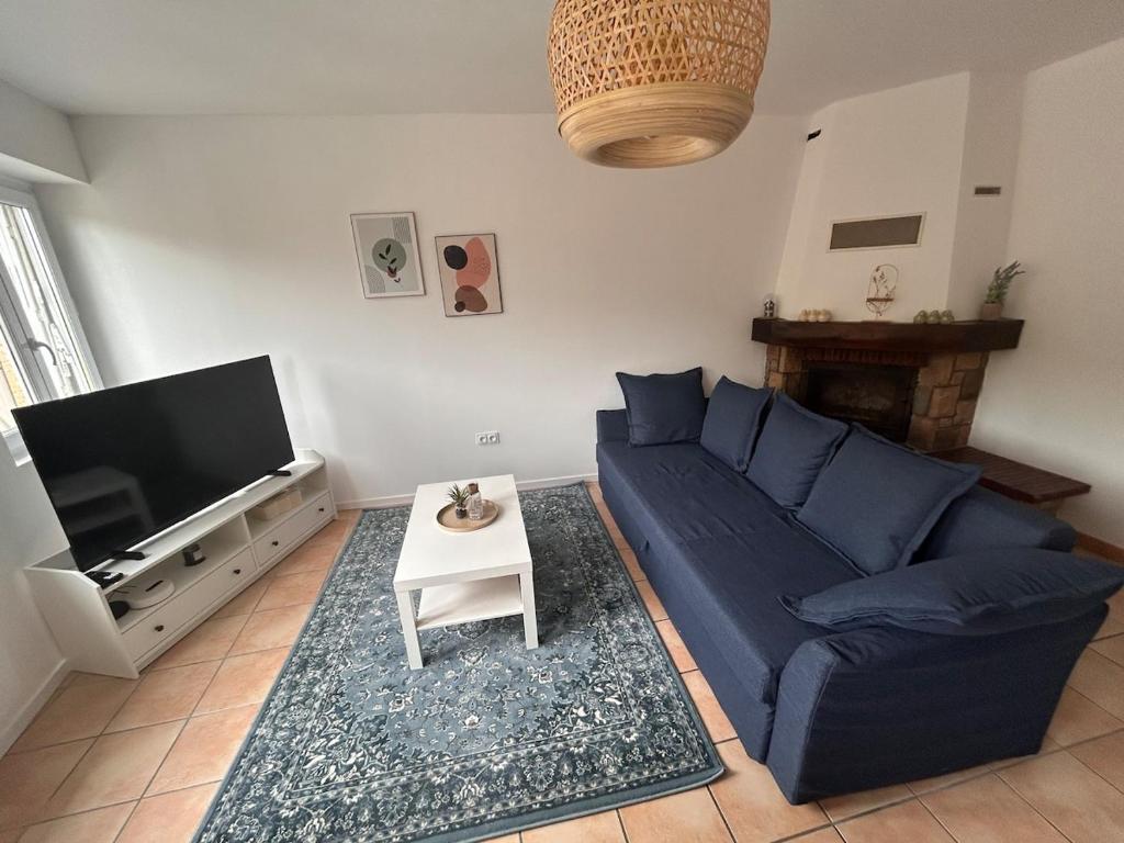 Petite maison au pied du château في Salignac Eyvigues: غرفة معيشة مع أريكة زرقاء وتلفزيون