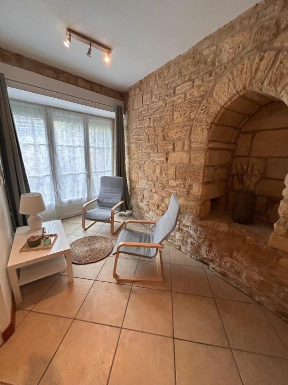 - un salon avec une cheminée en pierre et une chaise dans l'établissement Petite maison au pied du château, à Salignac Eyvigues