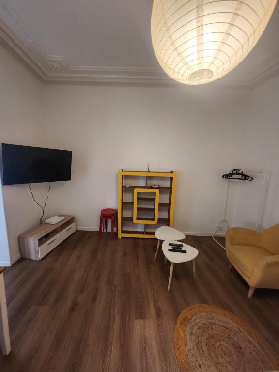 un salon avec une télévision à écran plat et un canapé dans l'établissement Le Ponsardin, à Reims