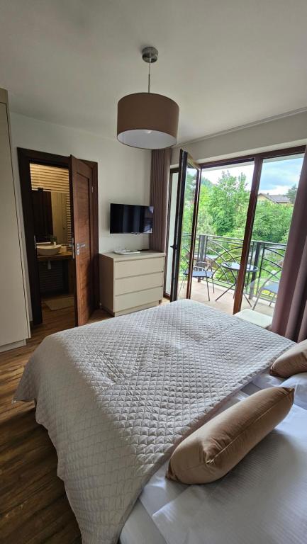 a bedroom with a large bed with a large window at Willa Zacisze Szczawnica 15 m2 in Szczawnica