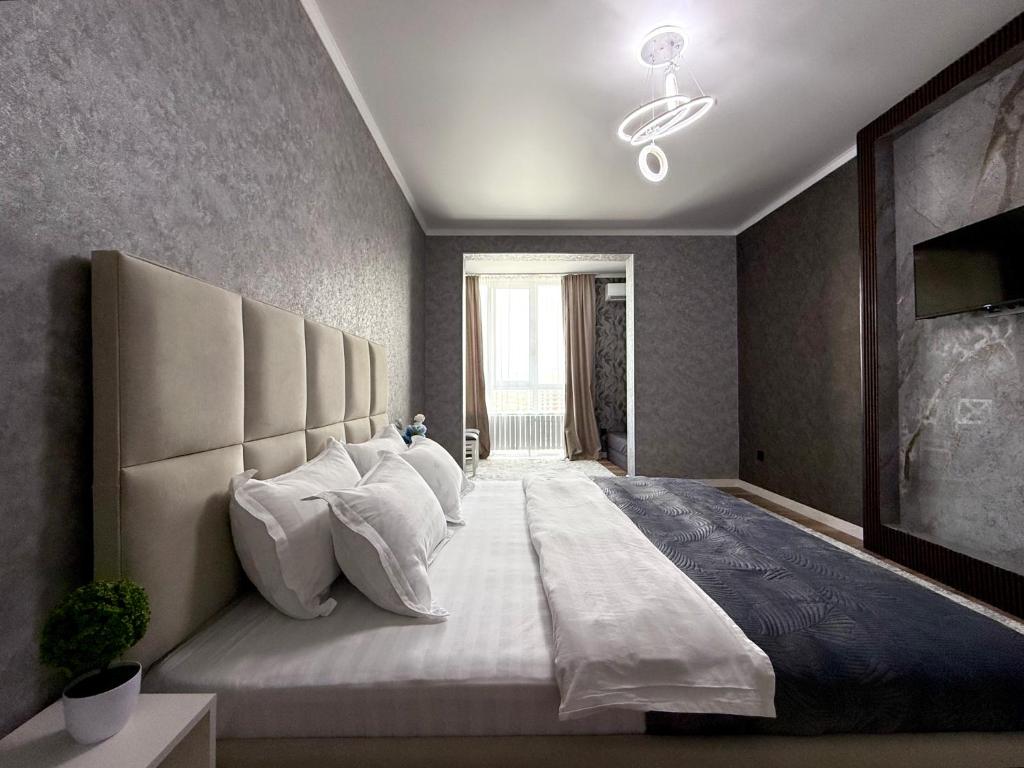 Un dormitorio con una cama grande con almohadas blancas. en Замечательная Раимбек резиденс 20-63 & питьевая вода подарок, en Almaty