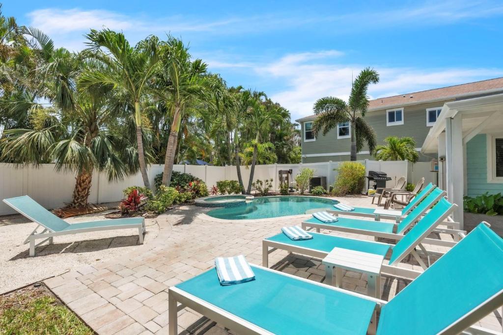 eine Terrasse mit blauen Stühlen und ein Swimmingpool mit Palmen in der Unterkunft Ebb Tide Home in Holmes Beach