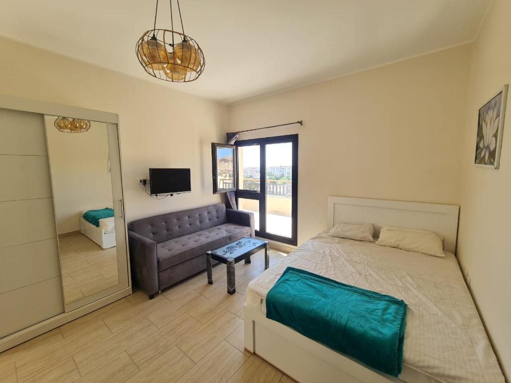 Un dormitorio con una cama, un sofá y un televisor. en AlDau Heights Modern Studio with Terrace, Mountain & City View, en Hurghada