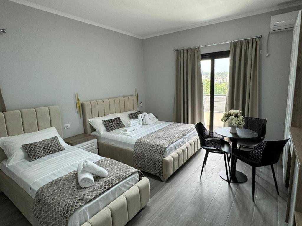 a hotel room with two beds and a table and a window at Hotel 4Palmat in Orikum